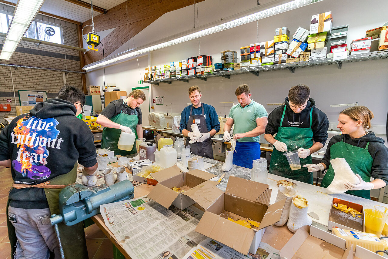 Auszubildende stellen gemeinsam Gipsmodelle von Füßen und Unterschenkeln in der Orthopädiewerkstatt her.