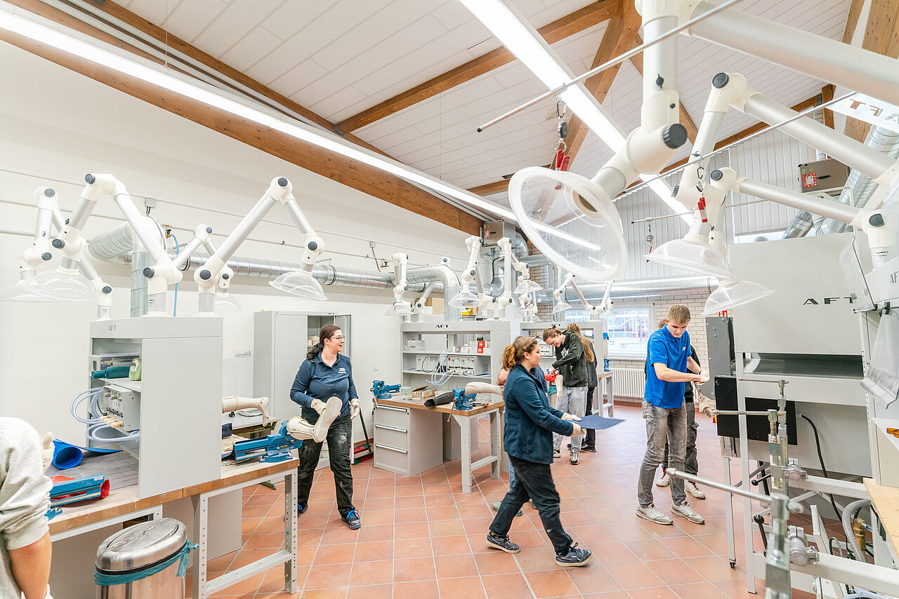 Schülerinnen und Schüler arbeiten an mehreren Werkbänken mit Gipsmodellen und orthopädischen Werkstücken.