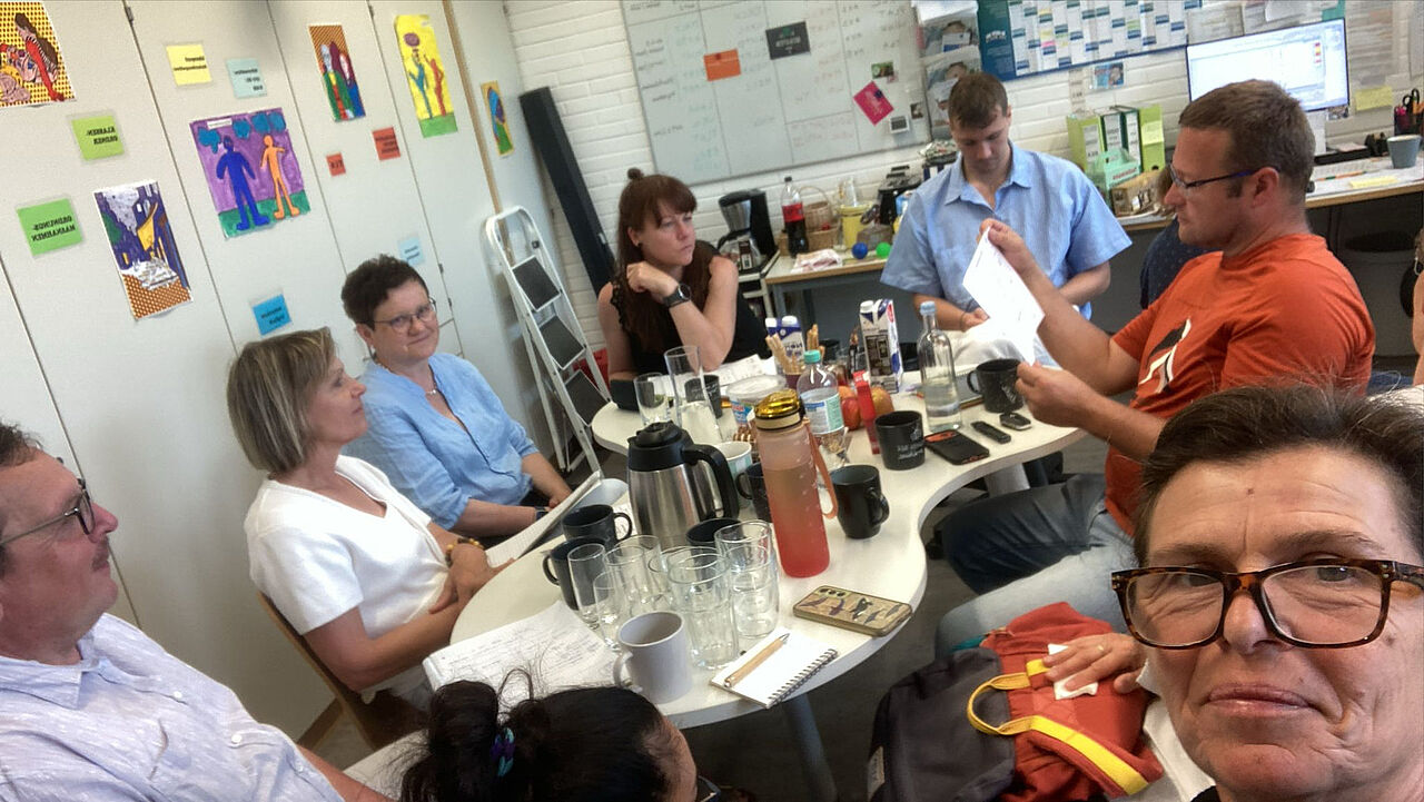 Pädagogische Fachkräfte sitzen bei einem Arbeitstreffen an einem Tisch und besprechen Unterlagen zum Tageslernen.
