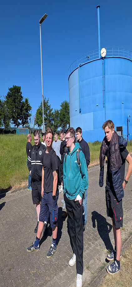 Schülerinnen und Schüler der Klasse SHK24 stehen während der Führung vor einem großen blauen Rundbehälter der Kläranlage Gotha.