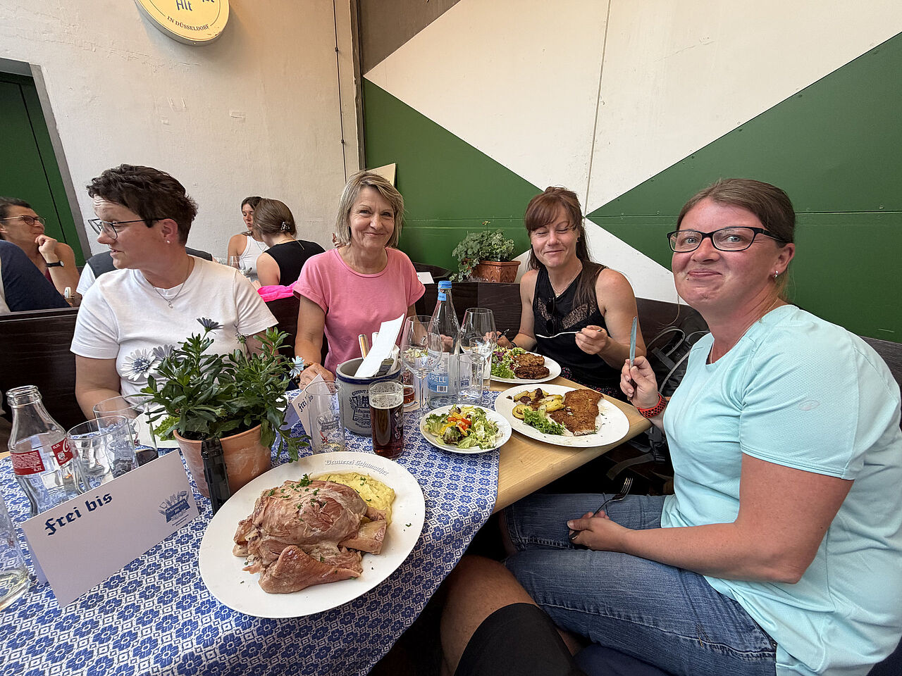 Vier Teilnehmerinnen sitzen beim gemeinsamen Mittagessen an einem gedeckten Tisch im Brauhaus.